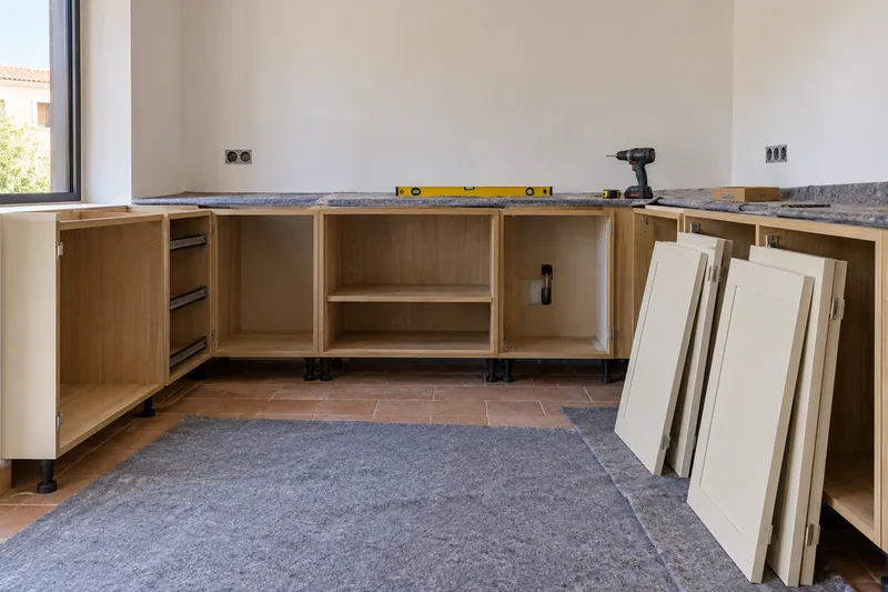 Visualización conceptual IA: Módulos de cocina en montaje con puertas pendientes de colocar.