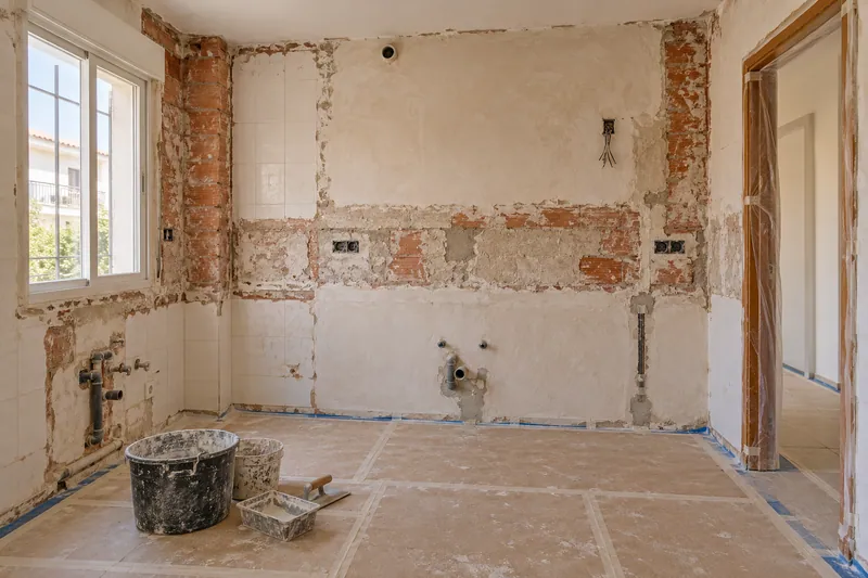 Visualización conceptual IA: Cocina sin muebles con paredes en preparación y zonas de enlucido.